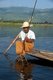 Burma / Myanmar: A leg rowing Intha fisherman shows off his skills with a large conical fish trap at Inle Lake, Shan State